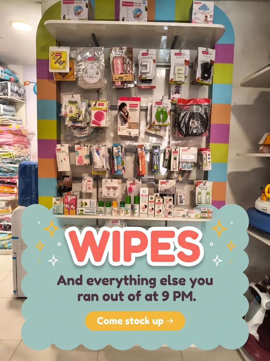 A full wall of baby essentials — wipes, feeding bottles, grooming kits and baby detergent, stacked shelf on shelf. Text on the photo: Wipes — and everything else you ran out of at 9 PM. Come stock up.
