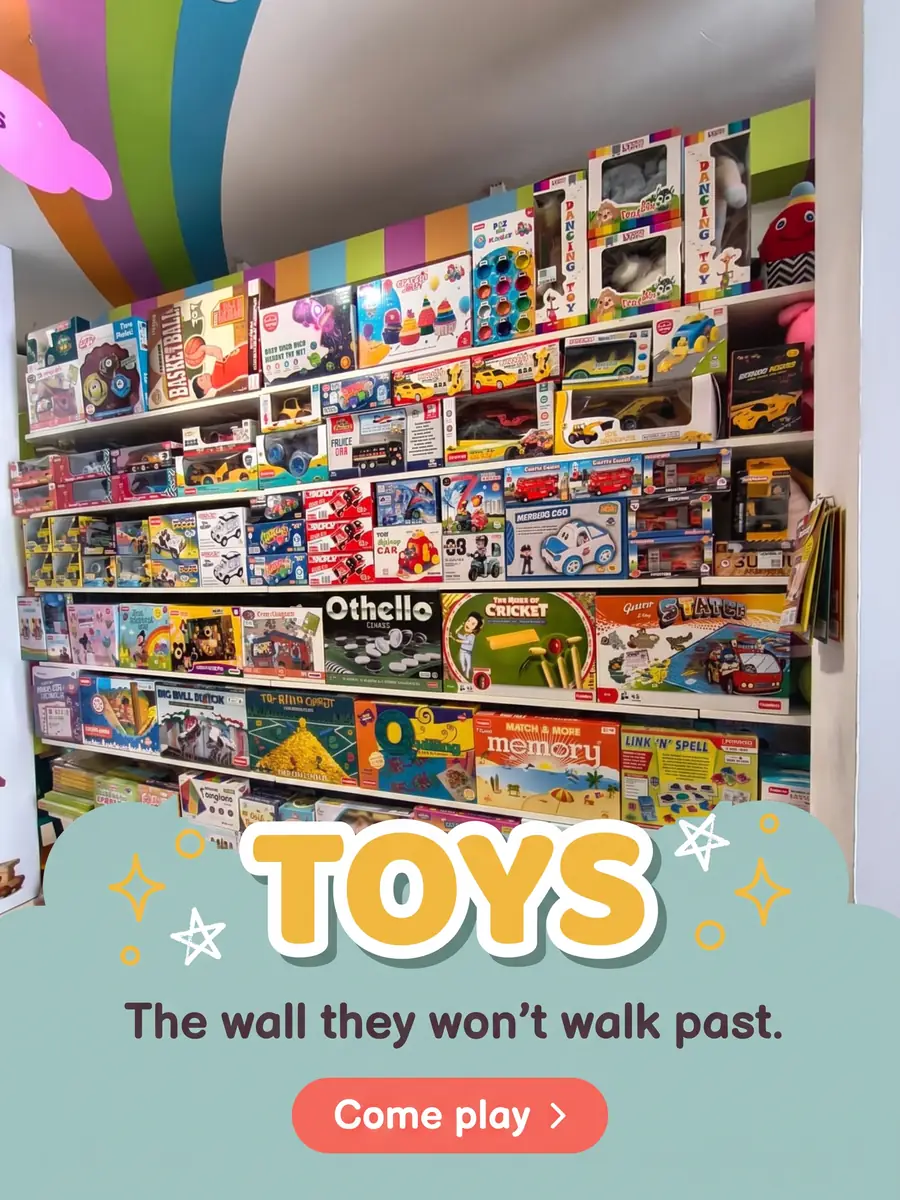 Shelves of boxed toys and board games including Othello, Memory and remote-control cars. Text on the photo: Toys — the wall they won't walk past. Come play.